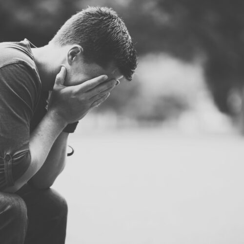 Black and white photo of a man sitting with his head in his hands