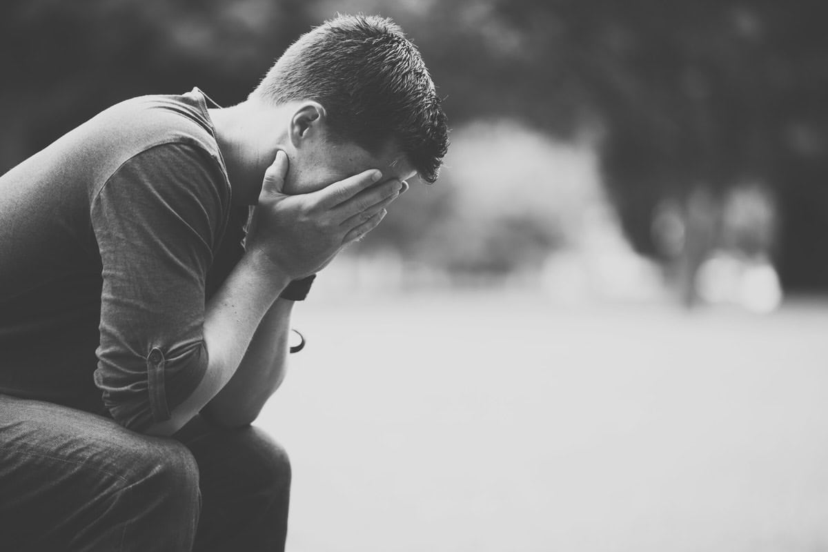 Black and white photo of a man sitting with his head in his hands
