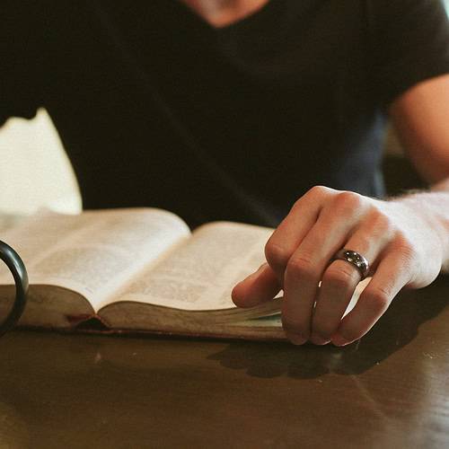 a seated man doing devotions at a table with coffee