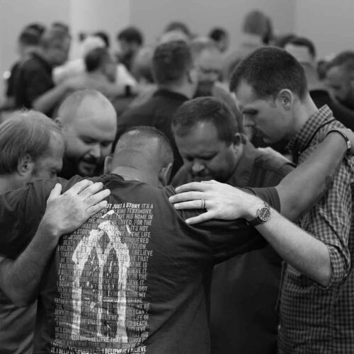 room full of small clusters of people praying