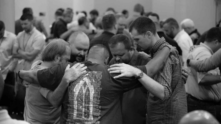 room full of small clusters of people praying
