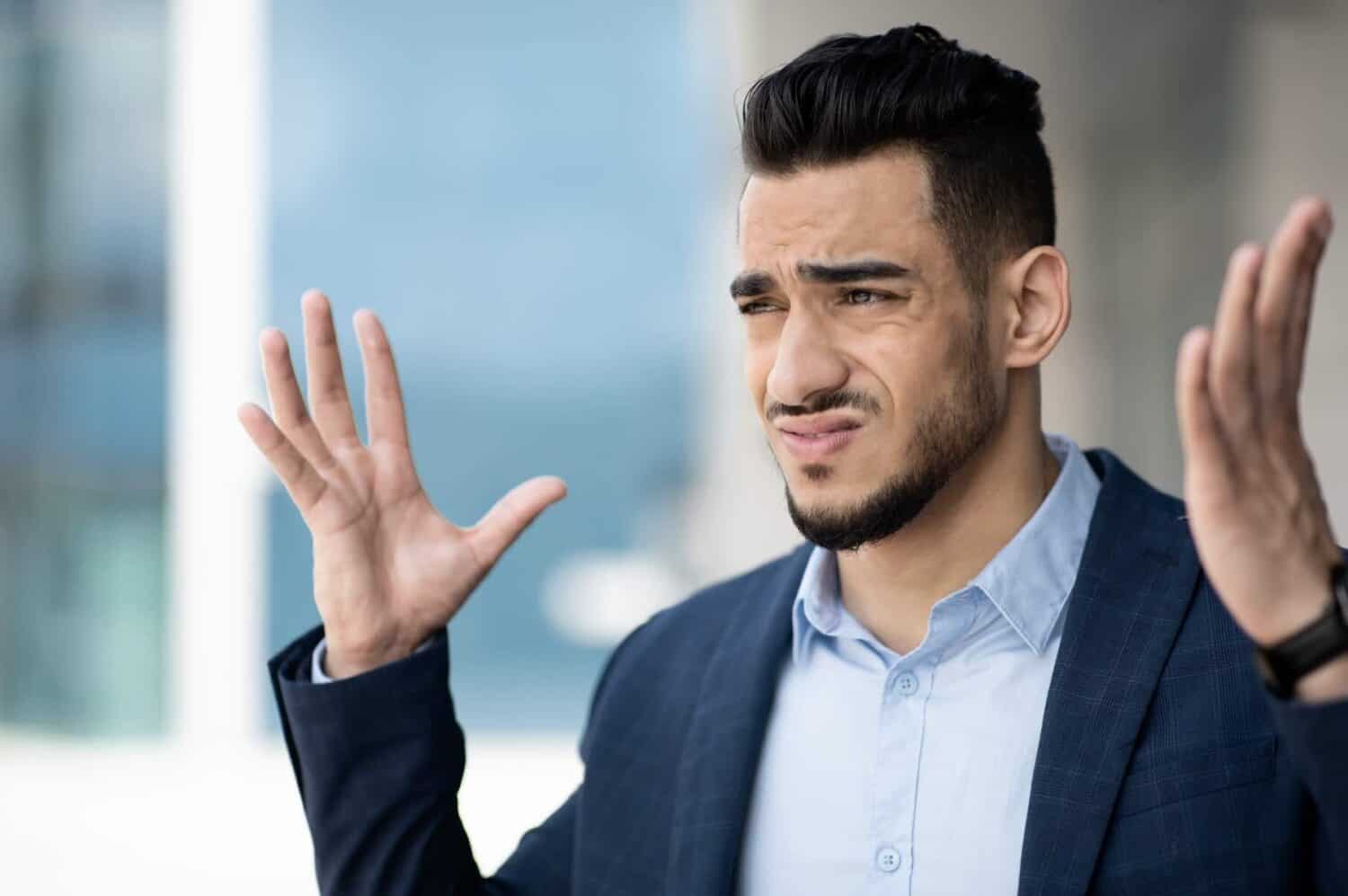 middle eastern man with hands up in frustration