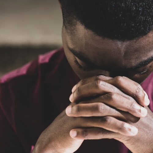 African man praying with face in clasped hands