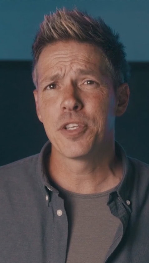 Man with spiky hair speaking to the camera