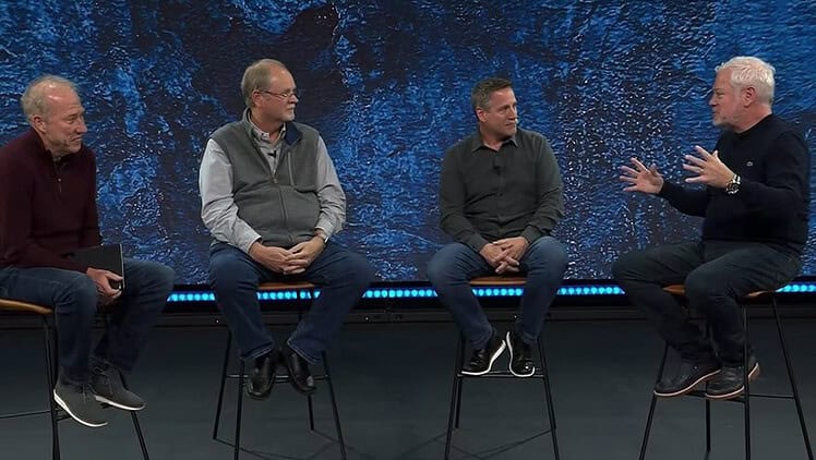 four men sitting on stools in a panel discussion