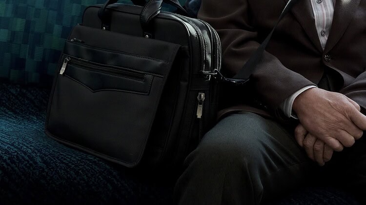 a train seat with a briefcase next to a man's lap to signify a bivocational pastor