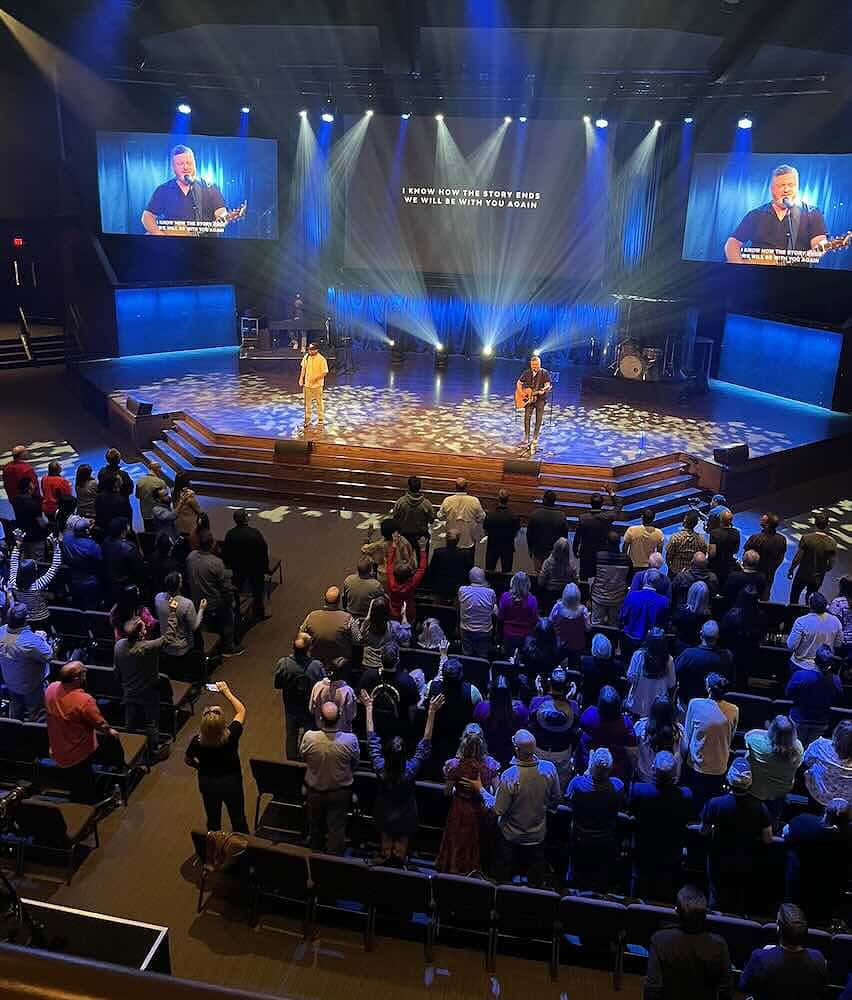 Room of worshipping people with Shane & Shane leading them