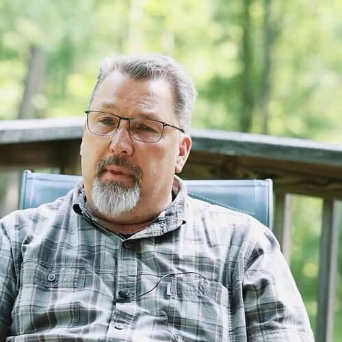 Man in a checkered shirt sitting on back deck
