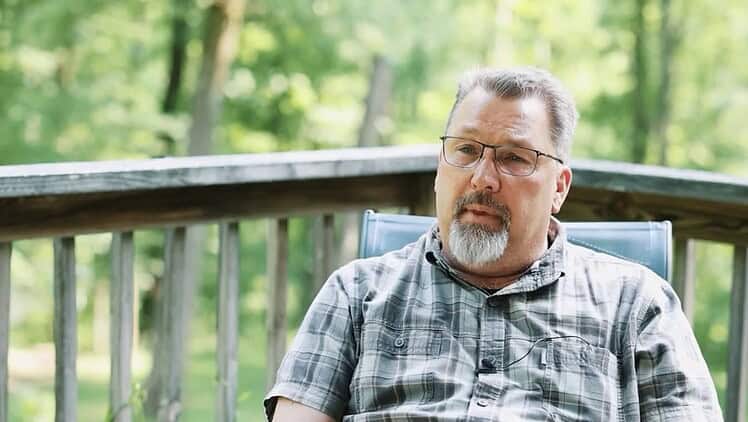 Man in a checkered shirt sitting on back deck