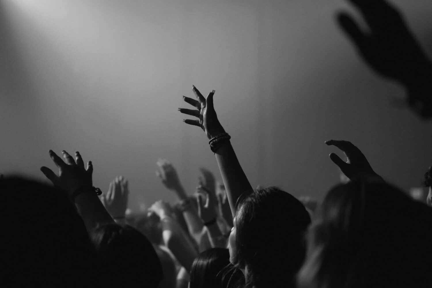 a congregation with their hands lifted in worship-based prayer