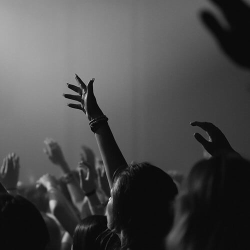 a congregation with their hands lifted in worship-based prayer