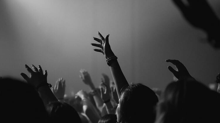 a congregation with their hands lifted in worship-based prayer