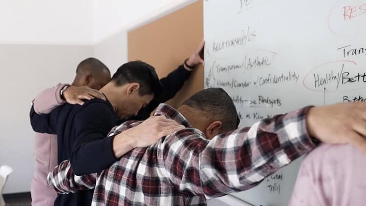 5 men praying -church staff -around white board