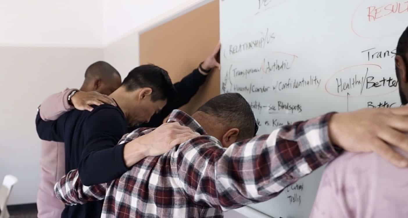 5 men praying -church staff -around white board