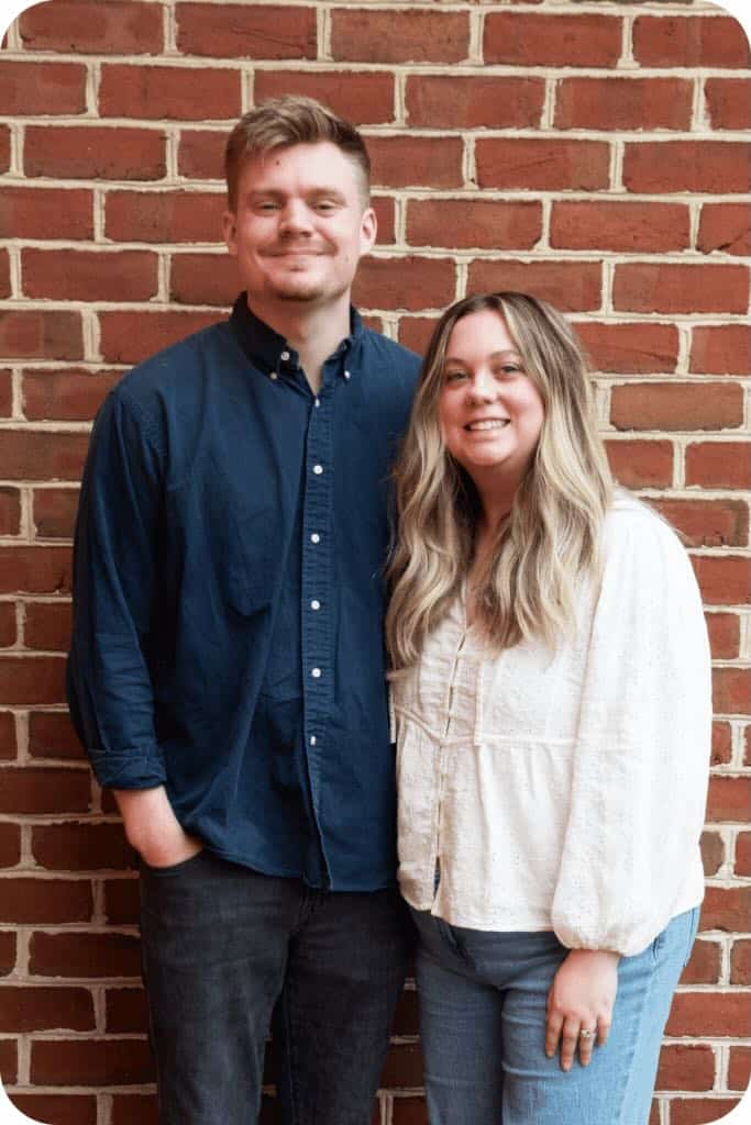 Man and wife standing on in front of brick wall
