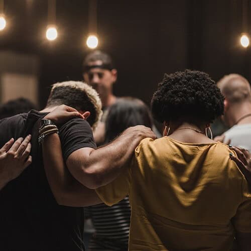 young adults gathered in a circle praying as a church