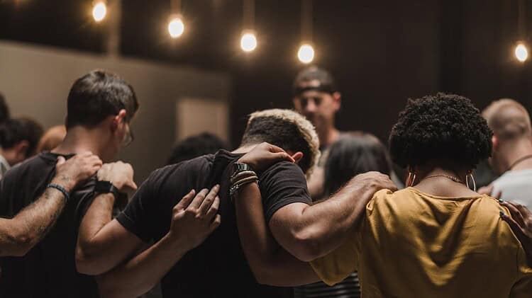 young adults gathered in a circle praying as a church