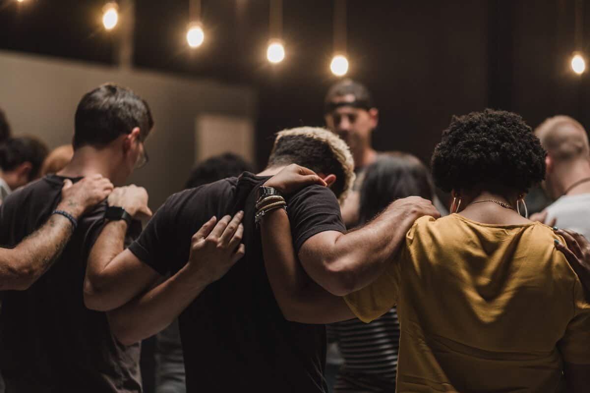 young adults gathered in a circle praying as a church