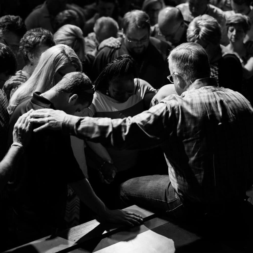 Group of people pray in a large group