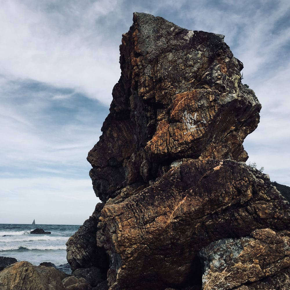 Sturdy looking rock formation by ocean