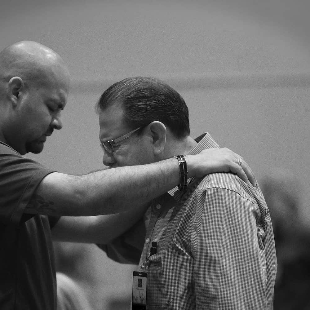 Two pastors praying together at an event.