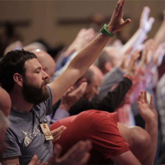 A group of pastors lift their hands in worship and prayer.