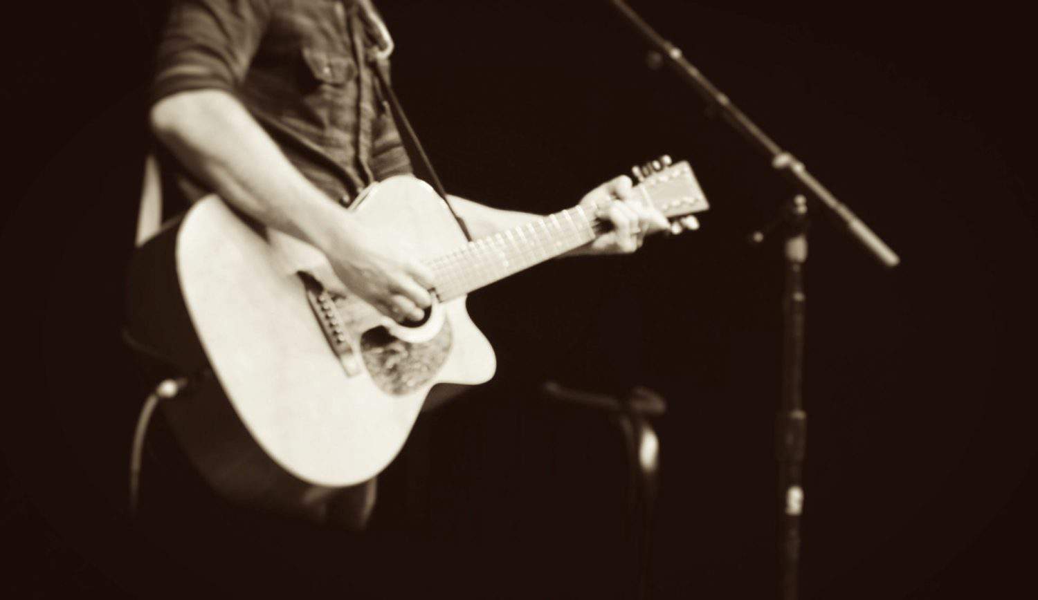 mand on stage with acoustic guitar