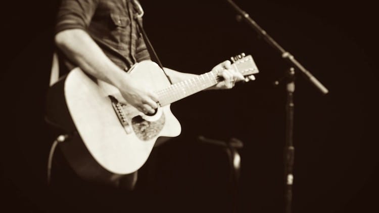 mand on stage with acoustic guitar