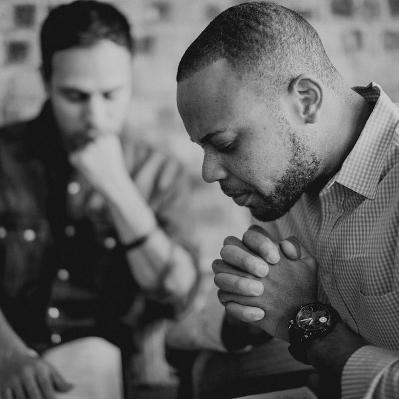 Two pastors pray with their eyes closed.