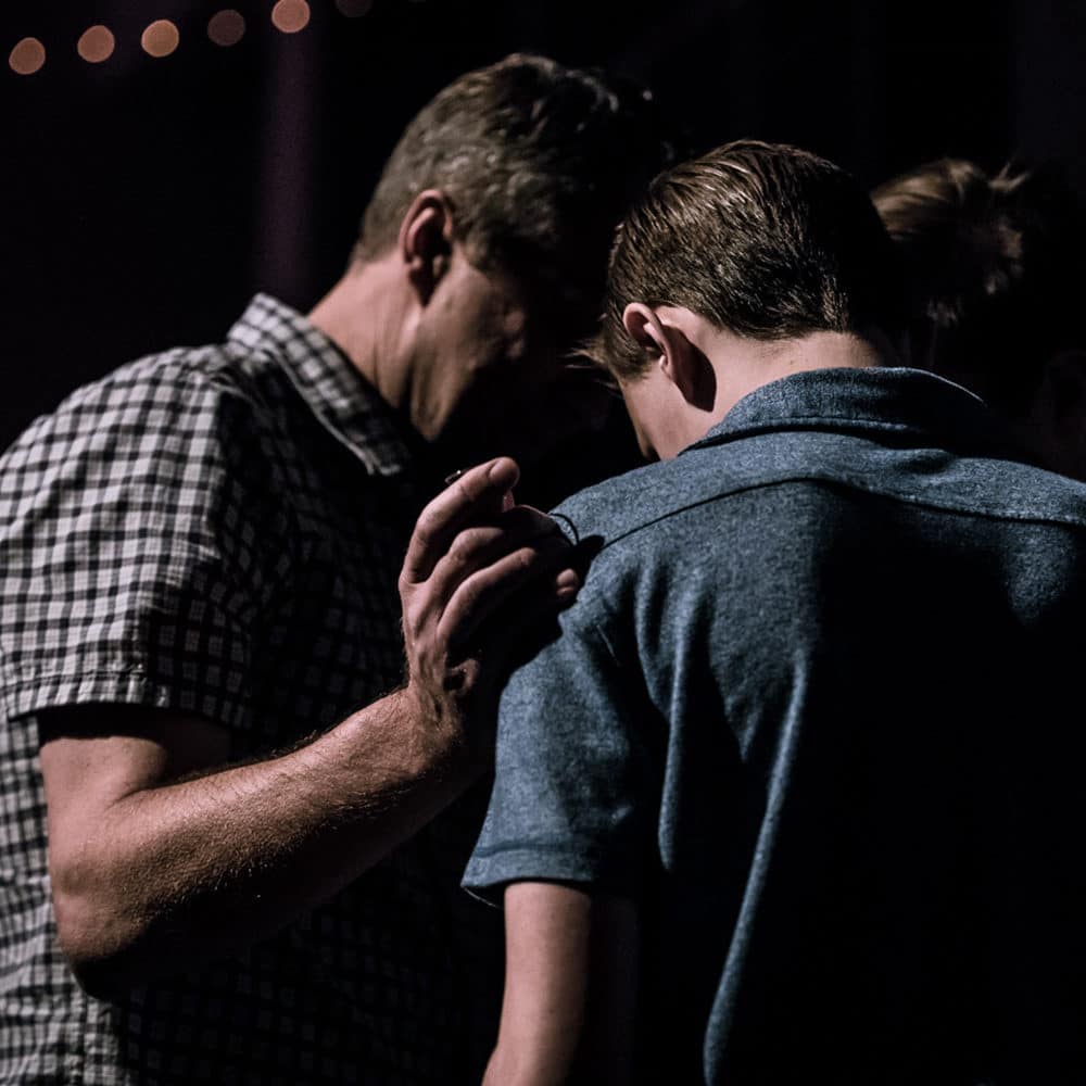 Pastor praying with church member